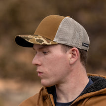 Man wearing duck camo Ridge Trucker Hat looking off to the side