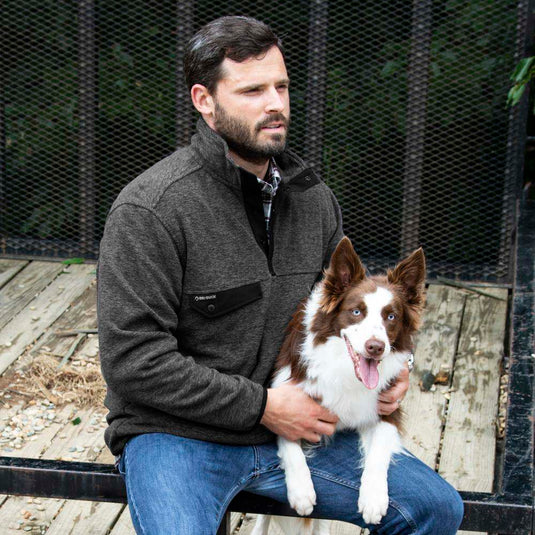 Man wearing charcoal Denali Fleece Pullover sitting outside with dog.