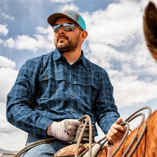 Man wearing navy Gillham Plaid Word Shirt while riding a horse 