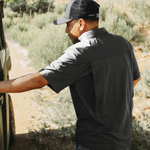 Man wearing charcoal Crossroad Short Sleeve Shirt while standing outside.