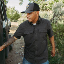 Man wearing charcoal Crossroad Short Sleeve Shirt while standing outside.
