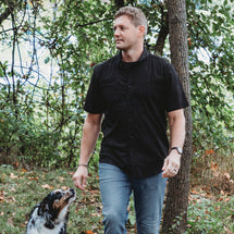 Man wearing black Craftsman Short Sleeve Shirt while walking with a dog outside. 