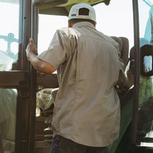 Man wearing rope Craftsman Short Sleeve Shirt while climbing into farm equipment