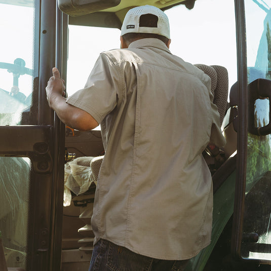 Man wearing rope Craftsman Short Sleeve Shirt while climbing into farm equipment