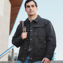 Man wearing charcoal Renegade Jacket walking downstairs with backpack