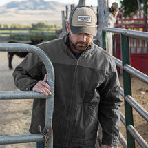 Man wearing black Horizon Canvas Jacket while opening fence outside