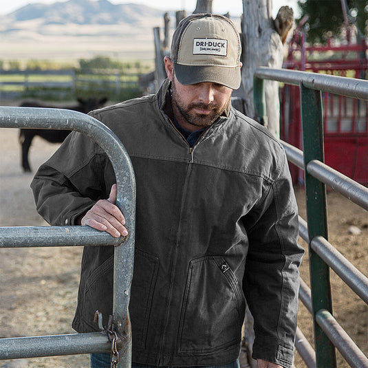 Man wearing black Horizon Canvas Jacket while opening fence outside