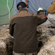 Man wearing tobacco Horizon Canvas Jacket standing facing away while working
