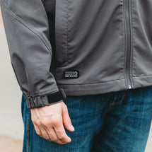Detail shot of charcoal Apex jacket showing adjustable hook and loop elasticized cuffs and exterior hand pockets with zipper closure