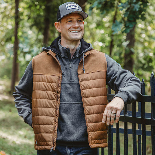 Man wearing saddle Summit Vest standing outside resting arm on fence