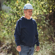 Man wearing navy Woodland hoodie standing in woods with hardhat