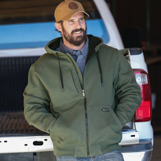 Man wearing fatigue Bateman zip up while standing outside truck