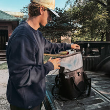 Man wearing navy Granite Crewneck while packing cooler in truck bed
