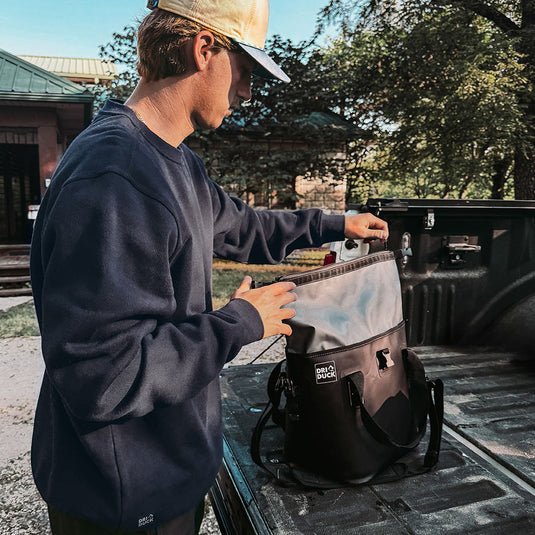 Man wearing navy Granite Crewneck while packing cooler in truck bed