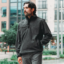 Man wearing charcoal Ranger Men's Fleece Pullover while standing in city center.