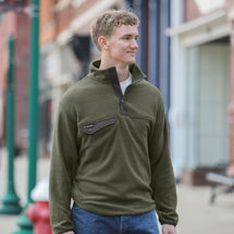 Man wearing sage Brooks Fleece Pullover standing outside.