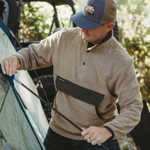 Man wearing moss Timber Men's Fleece Pullover assembling tent outside