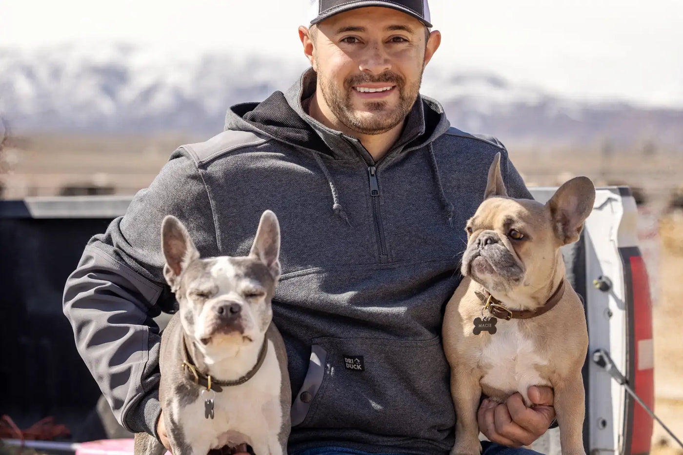 Customer featured outdoors with dogs, wearing the Mission Quarter Zip jacket by DRI DUCK.