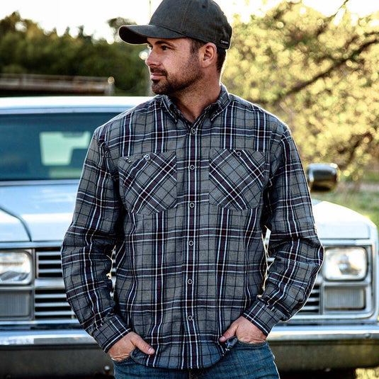 Man wearing grey and red Westwood Plaid Shirt standing outside with hands in pocket.