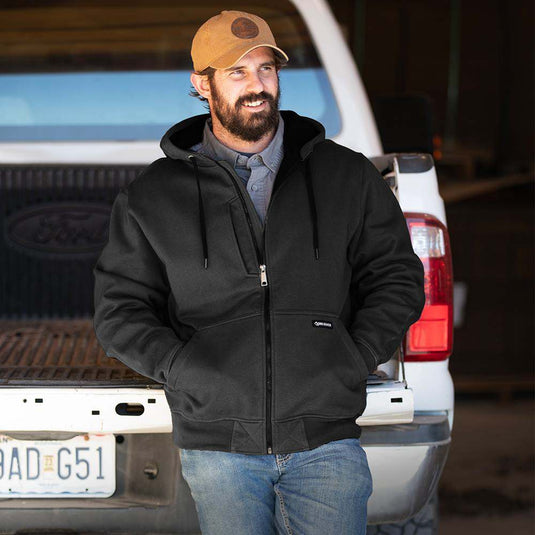 Man wearing black Bateman zip up while standing outside truck