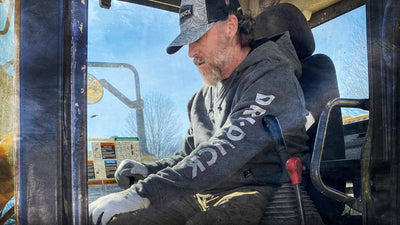 Man wearing Dri Duck territory trucker hat and fleece hoodie.